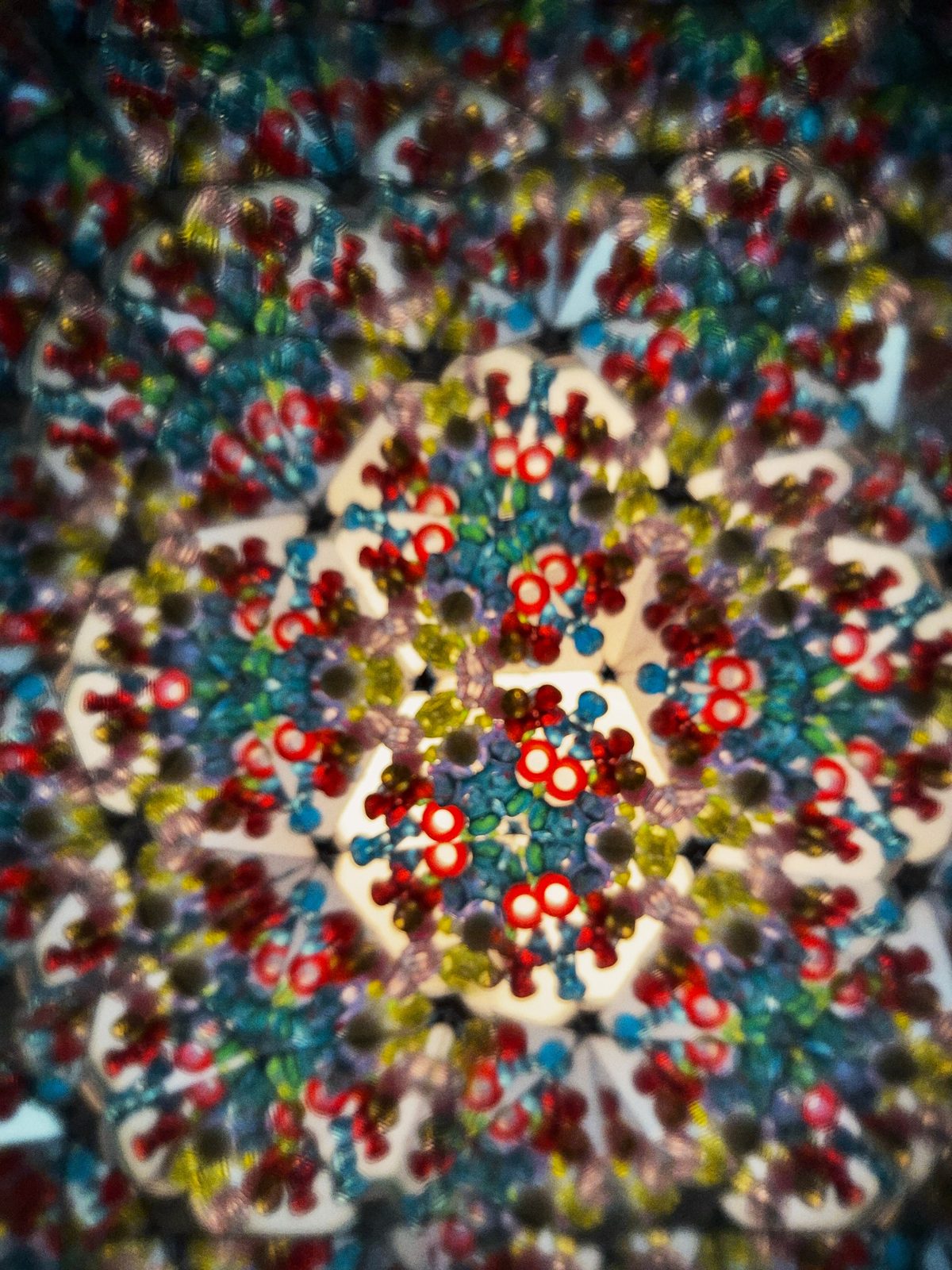 A kaleidoscope pattern of red, blue and yellow shapes, photographed through old glass